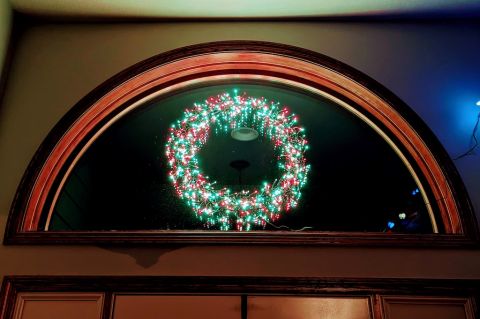 Lighted Christmas Wreath Hanging Above Door